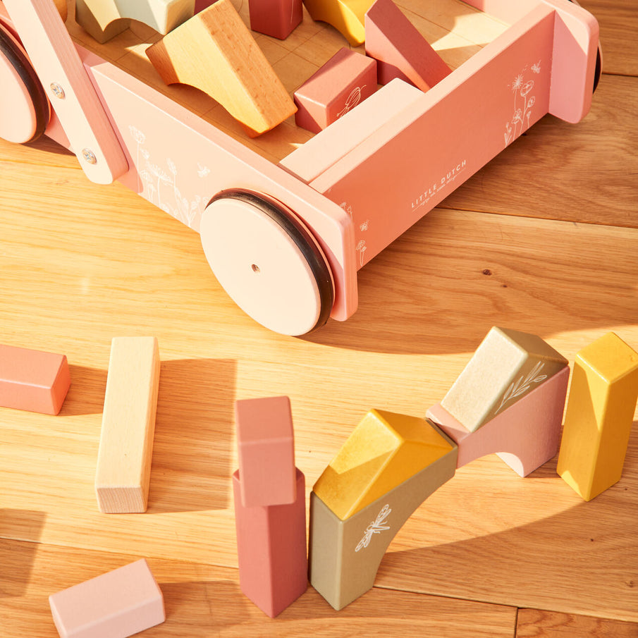 Chariot à blocs en bois et blocs empilés de couleurs pastel, posé sur parquet clair