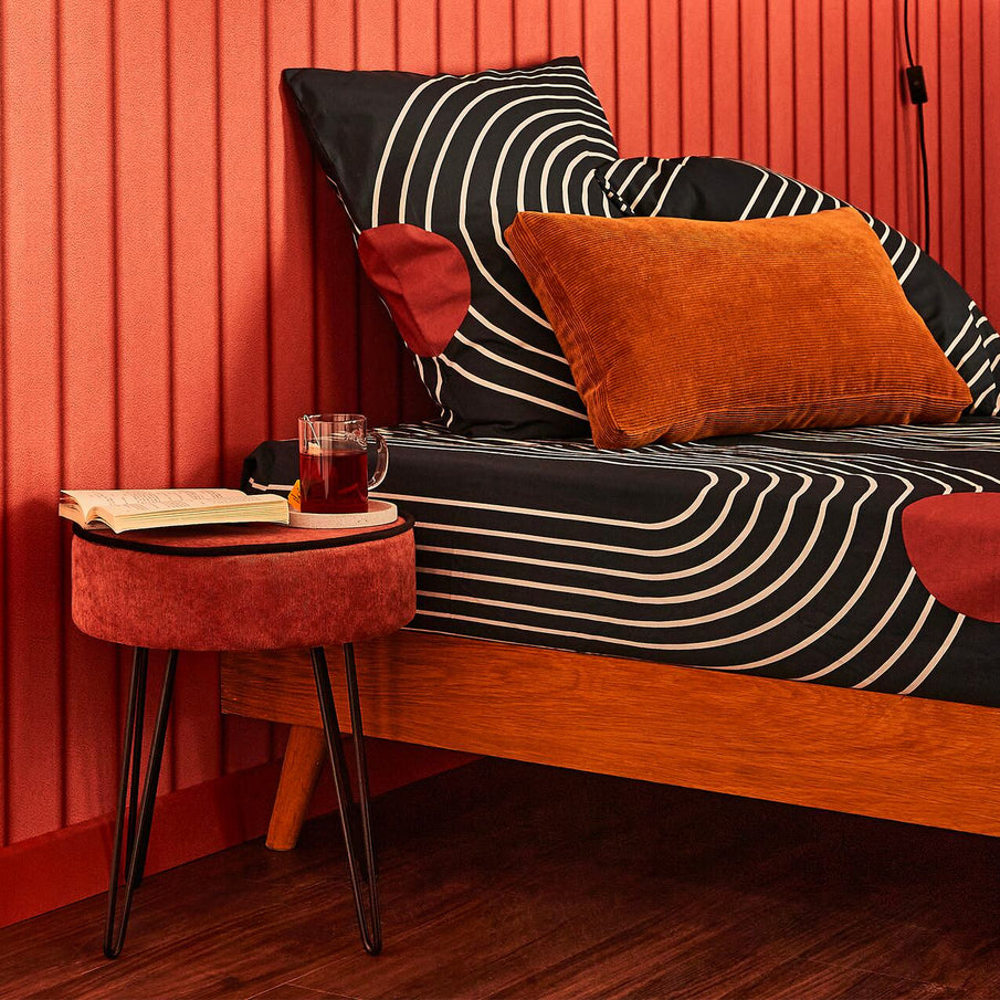 Tabouret en velours à côté d'un lit