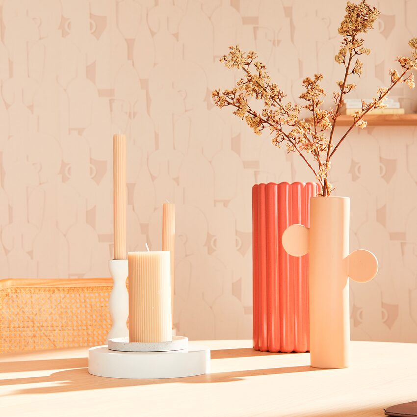 Trois bougies et deux vases aux couleurs beiges posés sur une table