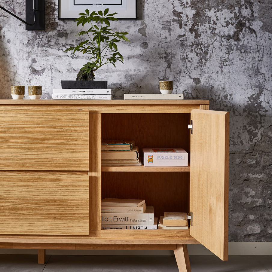 Buffet en bois clair avec porte ouverte devant papier peint effet pierre