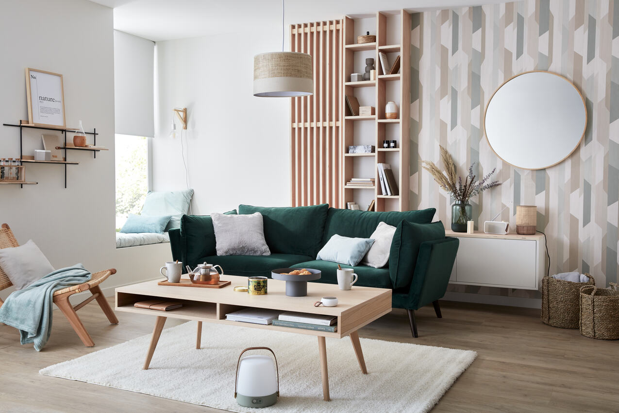 Salon style scandinave avec papier peint géométrique, canapé vert et mobilier en bois clair
