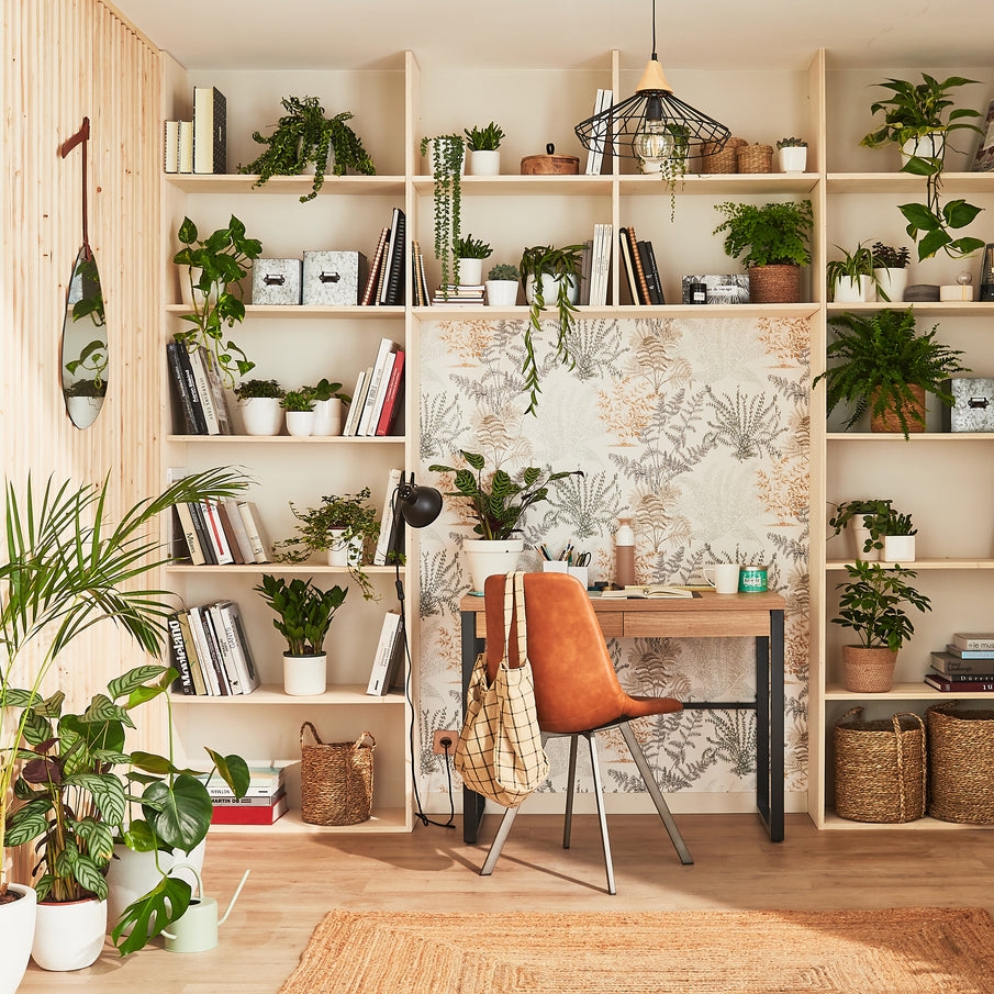 Bureau avec papier peint végétal et étagère murale avec plantes vertes et livres