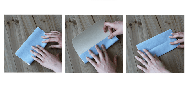 Mains pliant une feuille en origami en rabattant les côtés vers le pli central