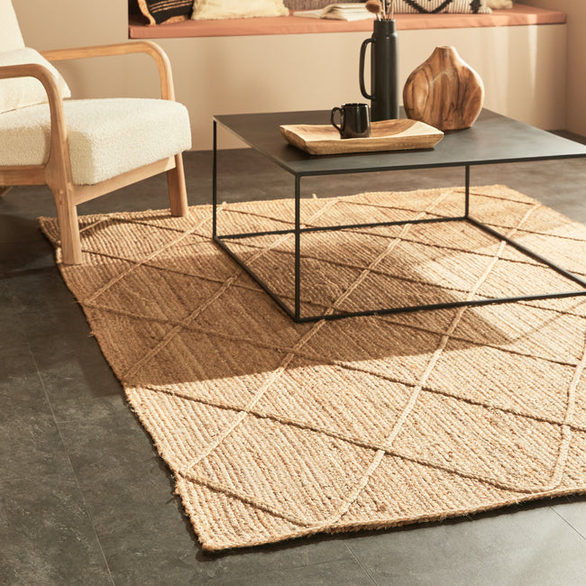 Tapis tressé en matière naturelle sous table basse métallique et fauteuil à bouclette