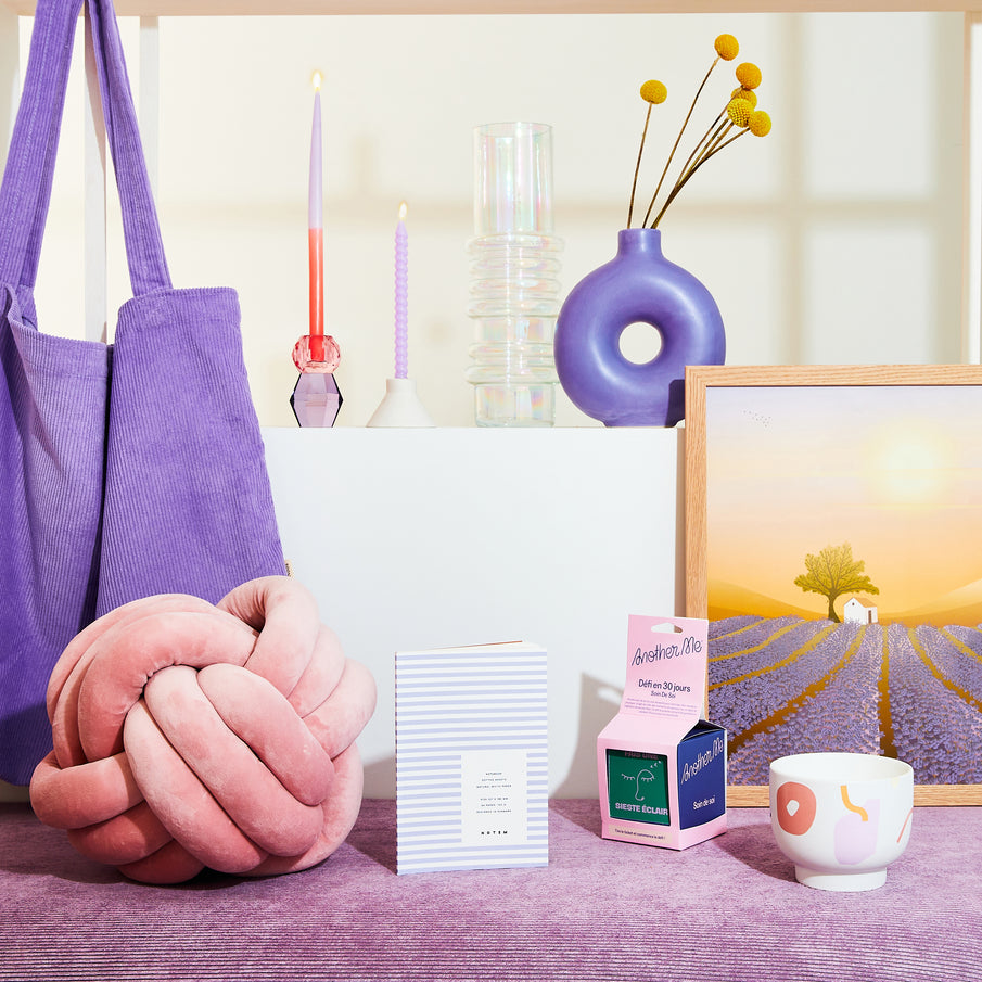 Accumulation d'objets dans les teintes de violet : coussin, carnet, vase, bougies, affiche