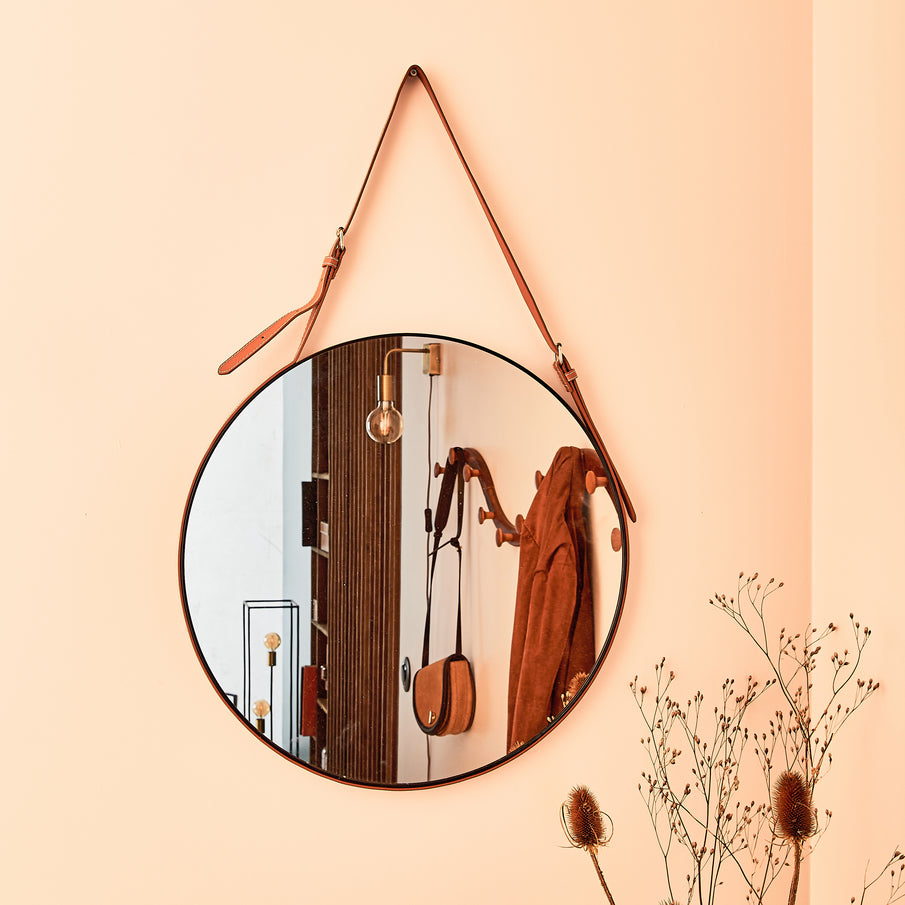 Zoom sur un miroir rond accroché dans une entrée