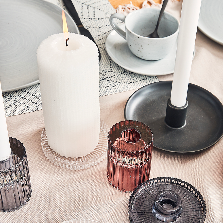 Bougeoirs en verre strié avec bougies blanches, posées sur une table