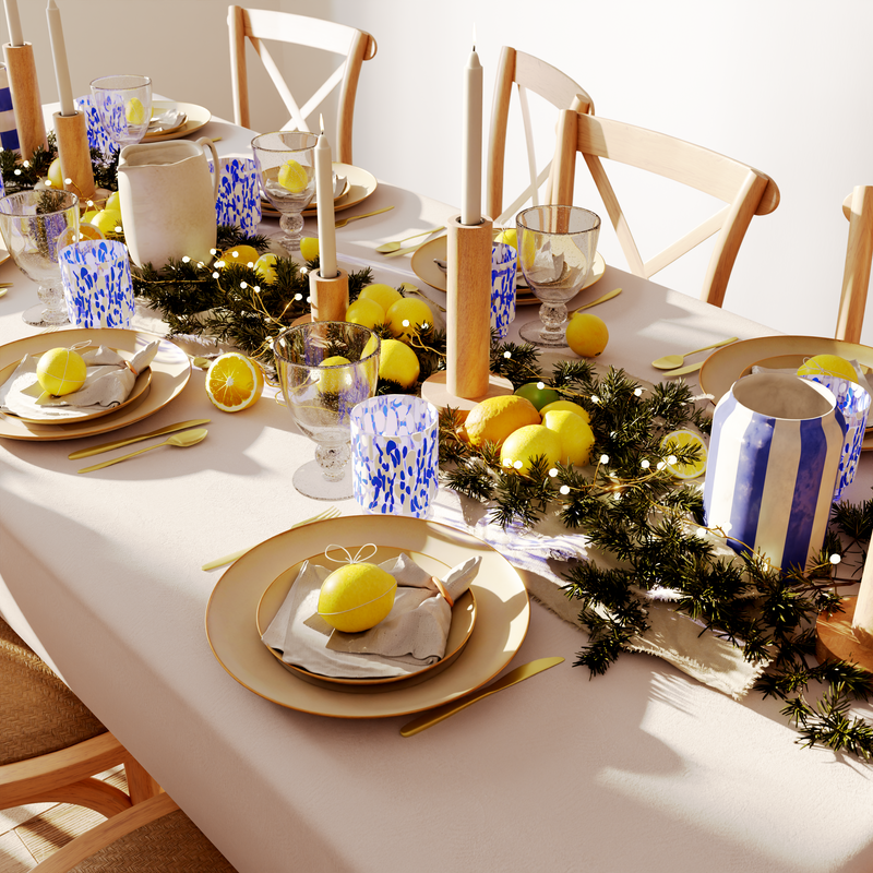 Table de fête naturelle avec des verres et vase en bleu et blanc et des agrumes en déco