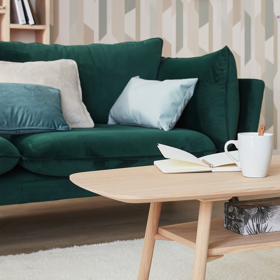 Table basse en bois clair, canapé en velours vert sapin