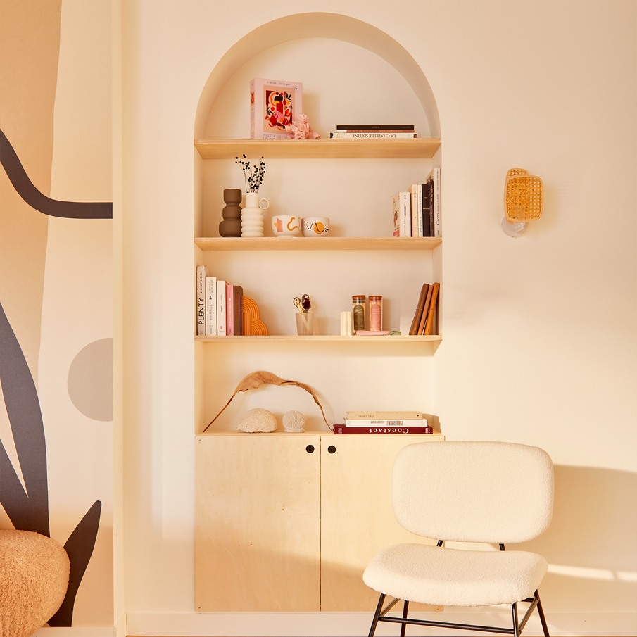 Bibliothèque dans une niche en forme d'arche, fauteuil et mur blancs