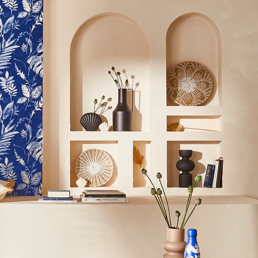 Bibliothèque dans niche en forme d'arche, déco noire et naturelle, papier peint bleu style cyanotype