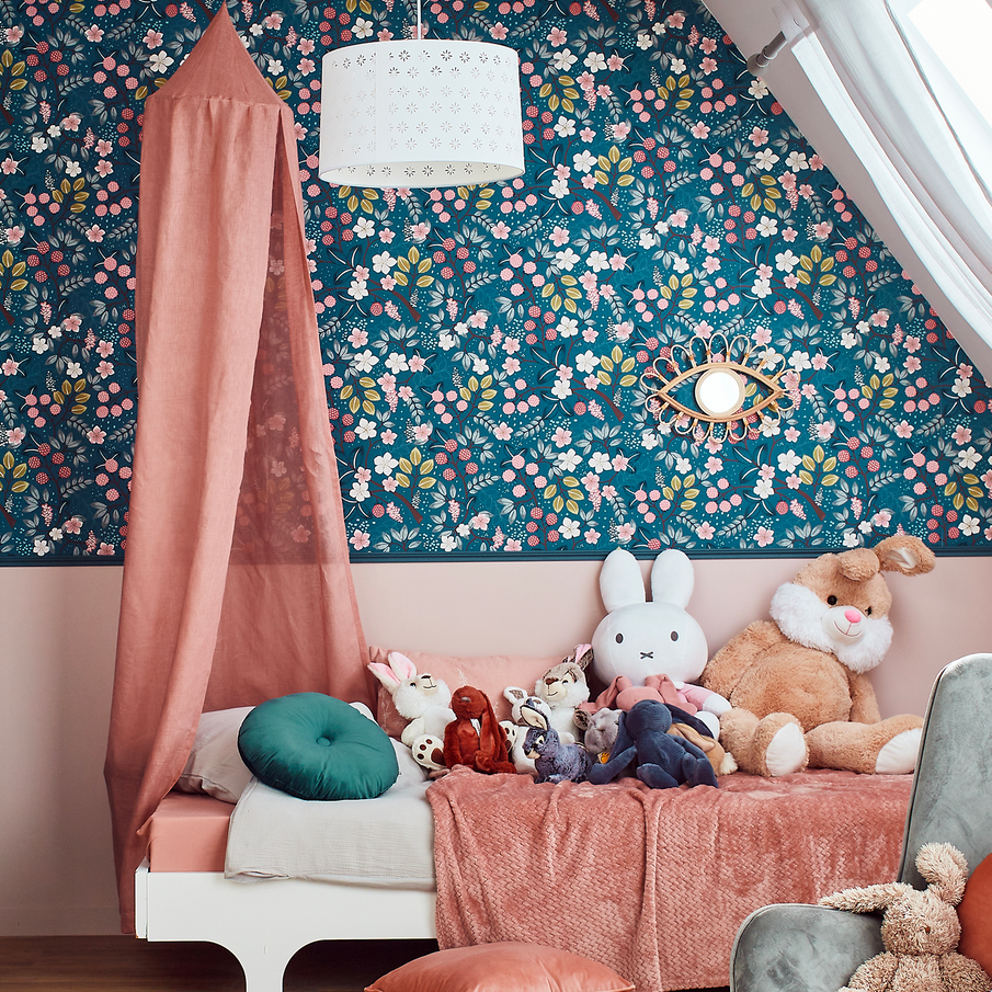 Chambre enfant aux tons roses avec papier peint bleu à motif floral blanc et rose