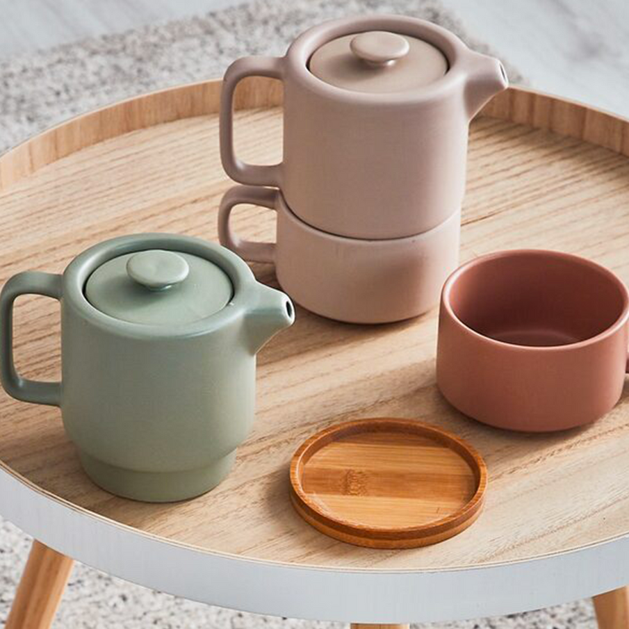 Deux théières rose et verte avec tasse et couvercle en bois sur table d'appoint