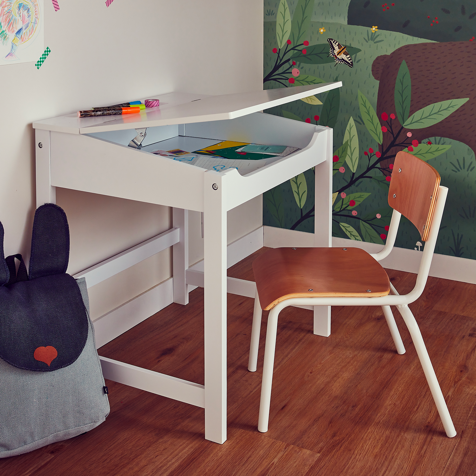Bureau blanc avec plateau soulevé et chaise en bois dans chambre d'enfant
