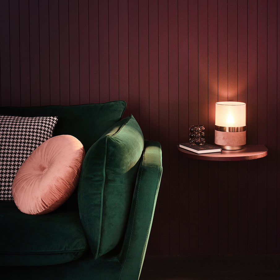 Canapé en velours vert foncé dans un salon au mur violet foncé et accessoires rose pale, style boudoir