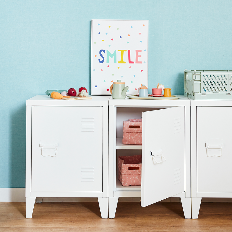 Casiers de rangement blanc avec jouets et déco pour enfants devant mur bleu pastel