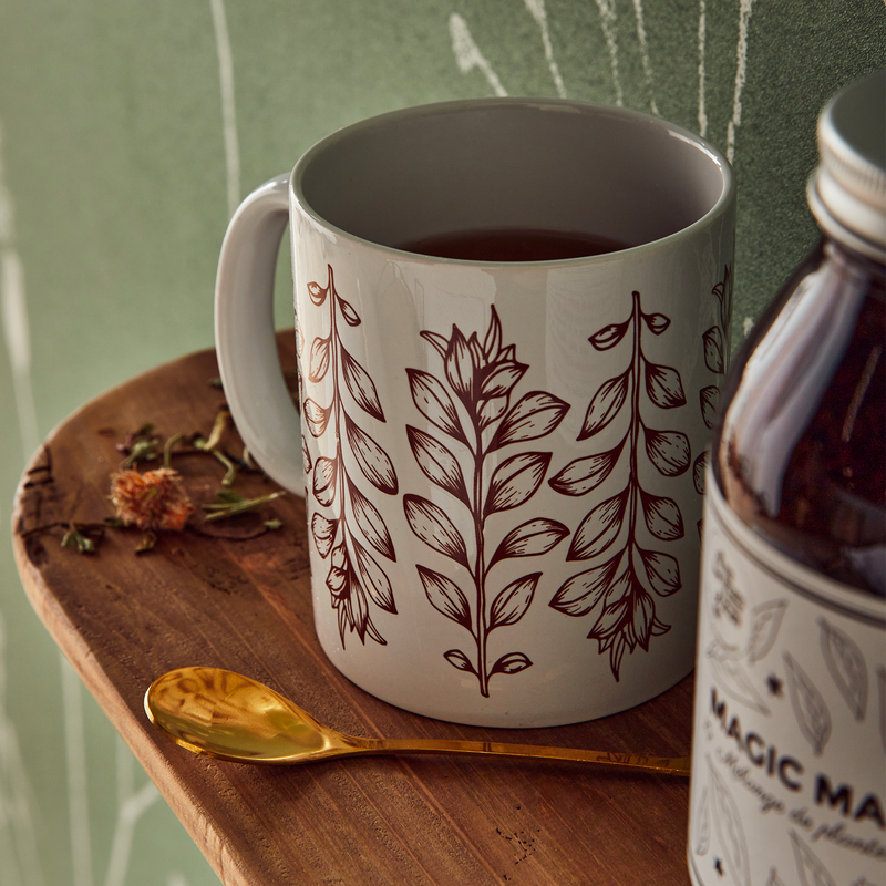 Mug à motif floral rouge avec du thé, posé sur une étagère