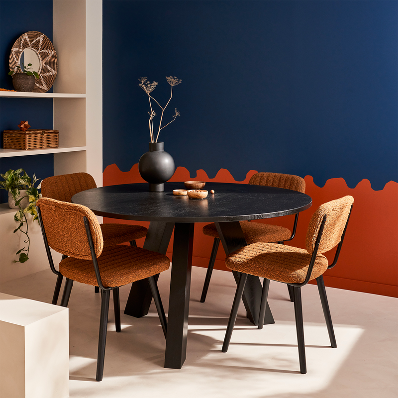 Coin repas avec table ronde en bois et mur peint en bleu foncé et orange