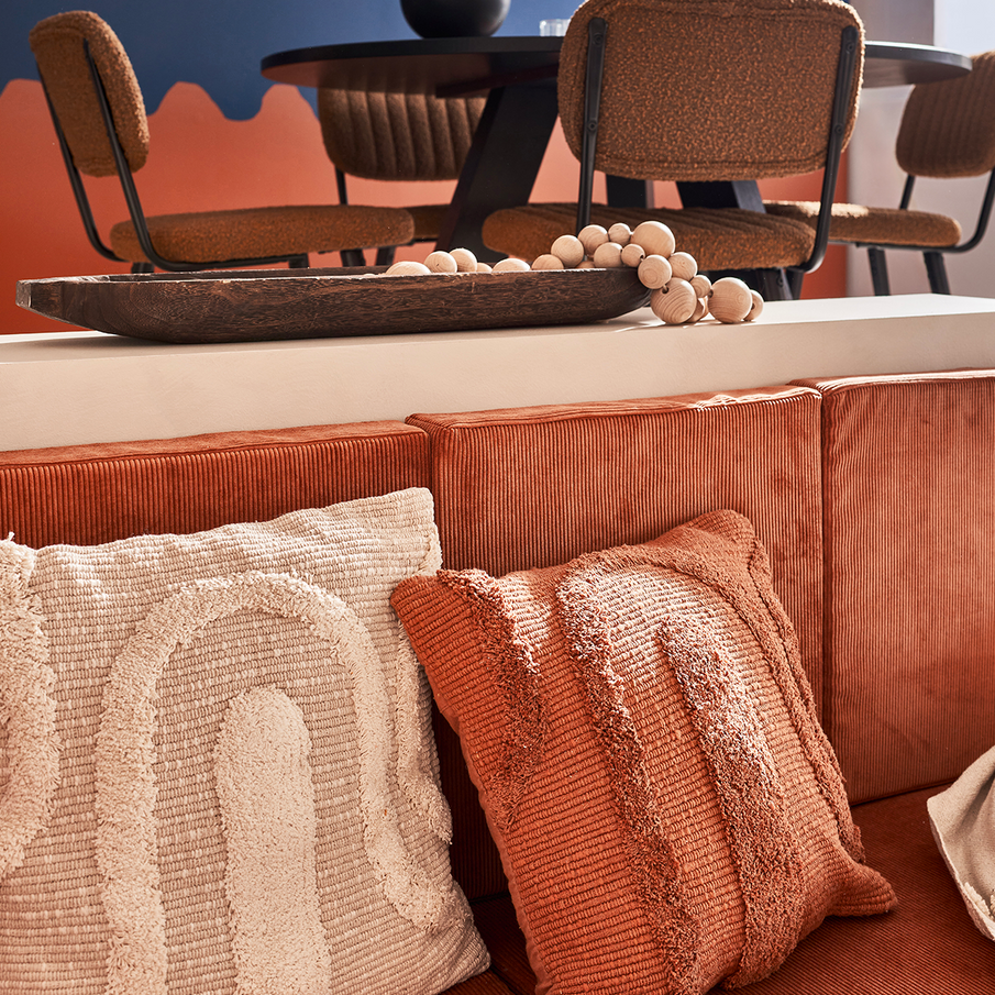Coussins tuftés beige et terracotta sur banquette de salon