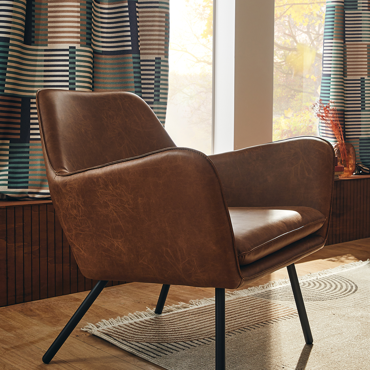 Fauteuil lounge en cuir devant fenêtre avec rideau bleu et brun à rayures horizontales