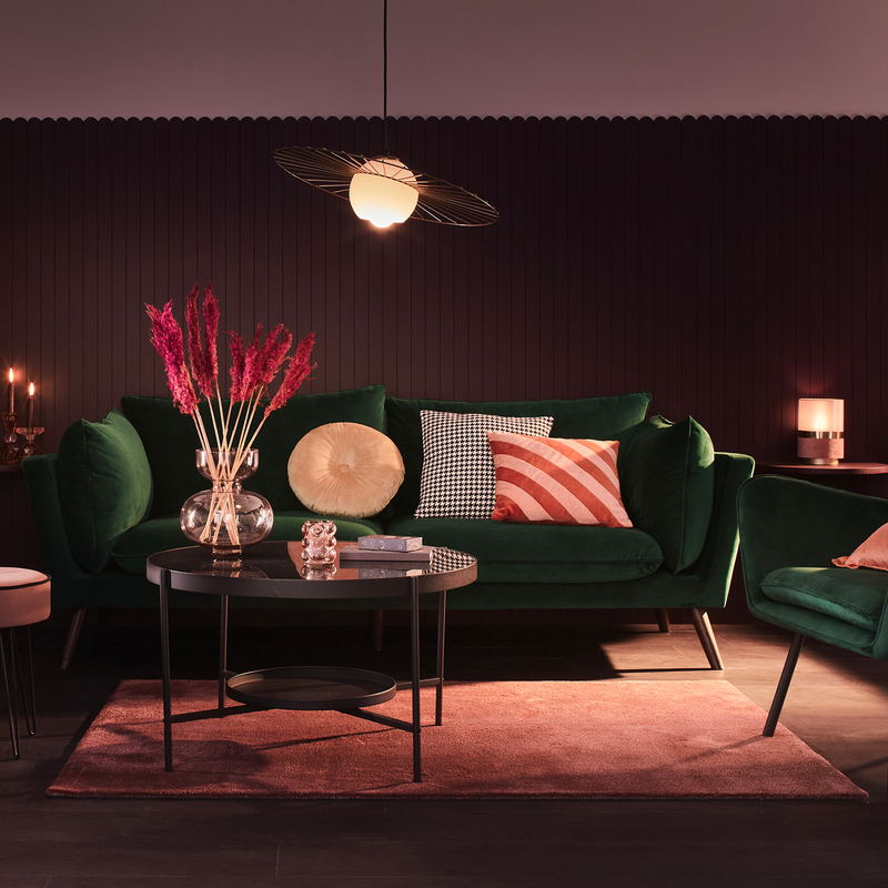 Tapis rose sous canapé vert et table basse noir métallique dans ambiance rosé tamisée