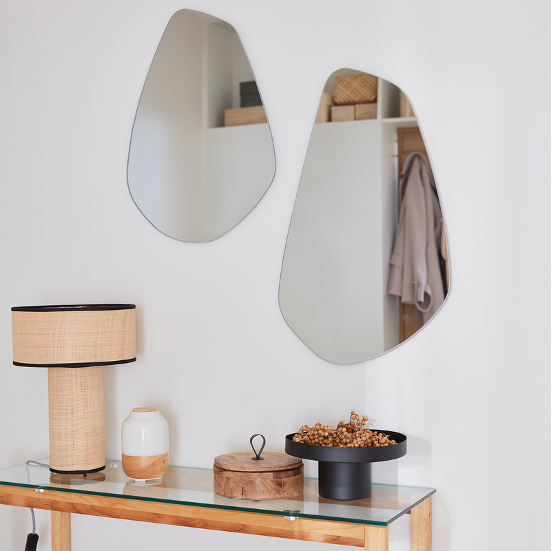 Deux miroirs à forme arrondie accrochés au-desssus d'une console à un mur blanc