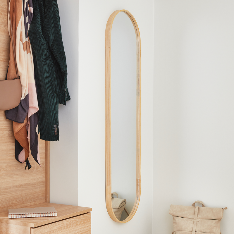 Grand miroir oval en bois accroché dans une entrée blanche
