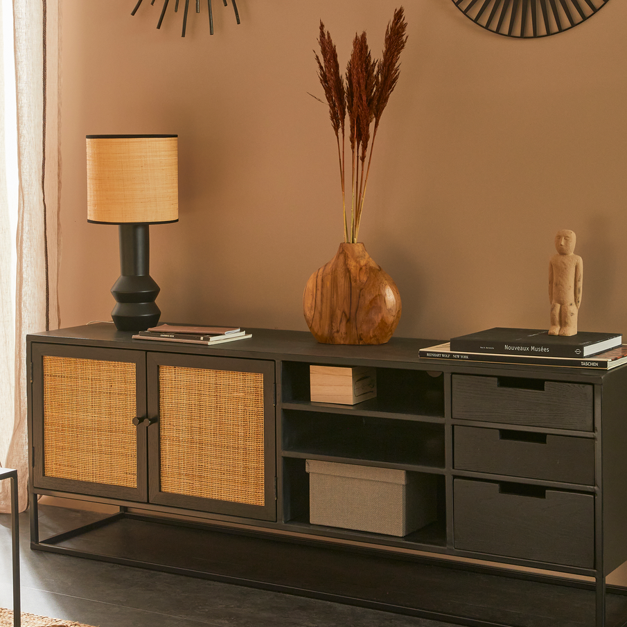 Meuble TV noir avec déco et lampe à poser devant mur brun