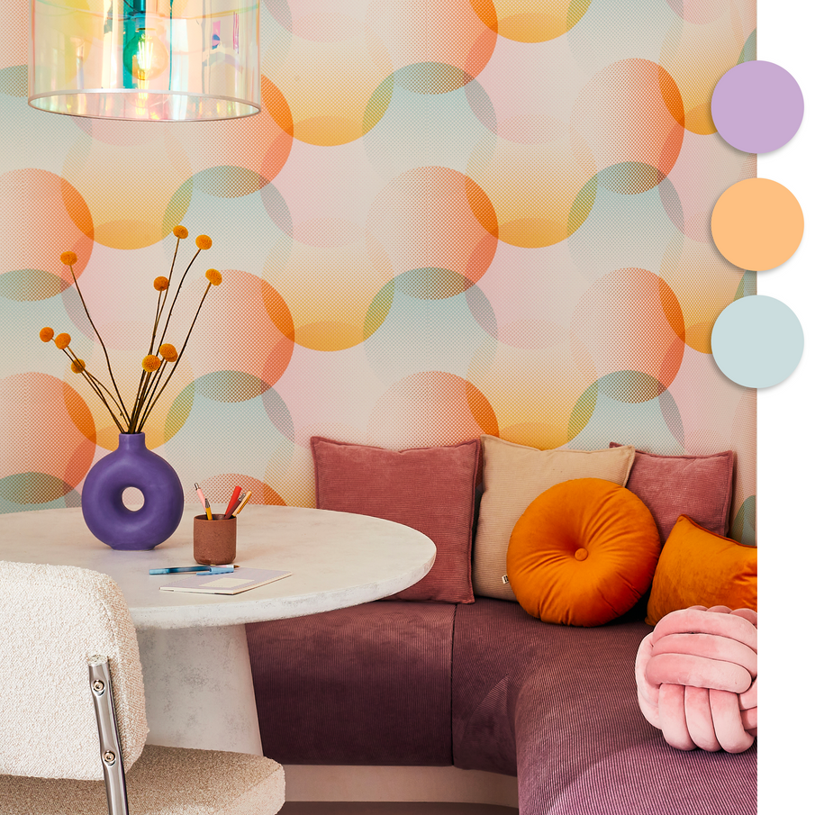 Papier peint motifs bulles pastel dans un coin repas avec table ronde en marbre blanc et banquette et coussins en velours