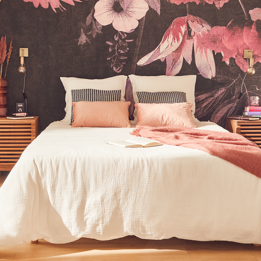 lit dans une chambre romantique avec papier peint motif fleurs XXL, parure de lit en gaze de coton blanc