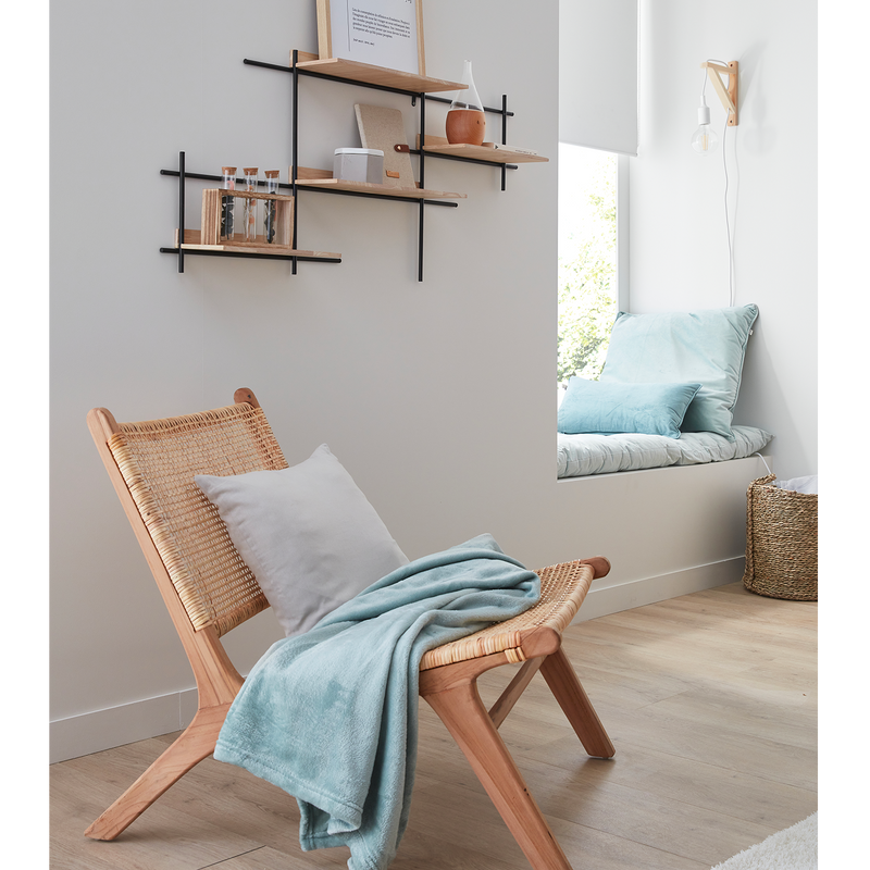 Coin salon avec fauteuil en osier et banquette avec coussins et plaid bleus