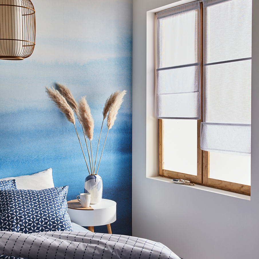 Fenêtre avec store bateau en lin dans une chambre bleue