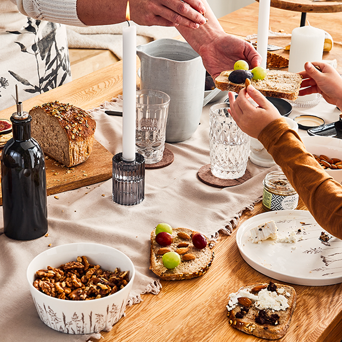 Mains tendant une tartine à une personne au-dessus d'une table dressée