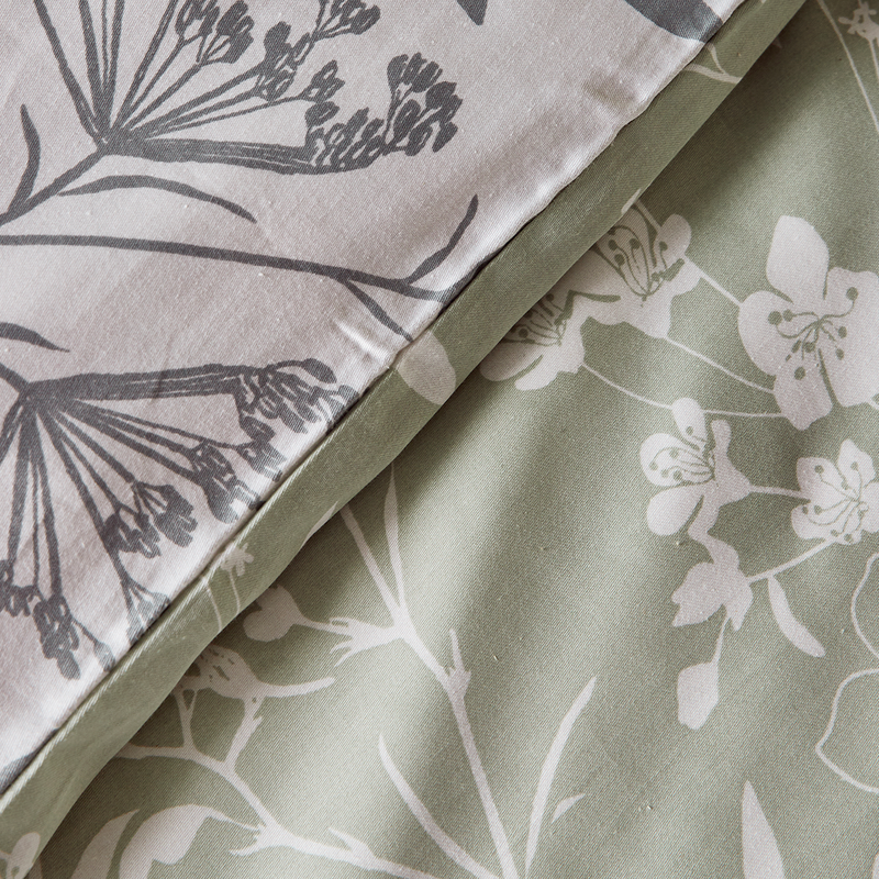 Photo cadrée sur le tissu d'une parure de lit en satin bio motif fleuri vert clair et blanc