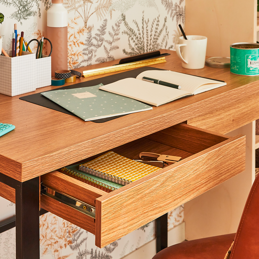 Bureau en bois avec tiroir ouvert et papeterie et tasse sur le plateau