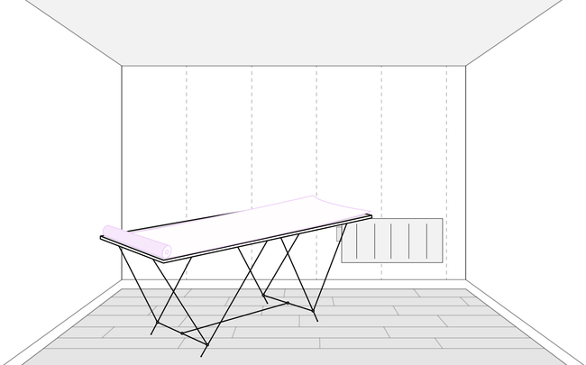 Rouleau de papier peint déroulé sur une table à tapisser dans une pièce