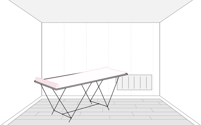 Rouleau de papier peint déroulé sur une table à tapisser dans une pièce