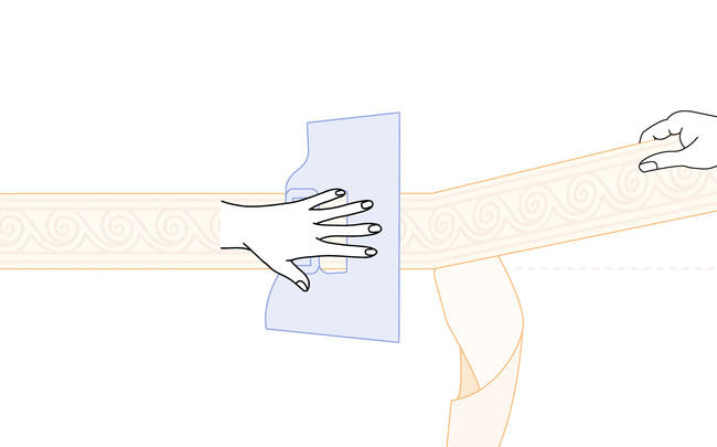 Main tenant une spatule à maroufler pour poser une frise adhésive au mur