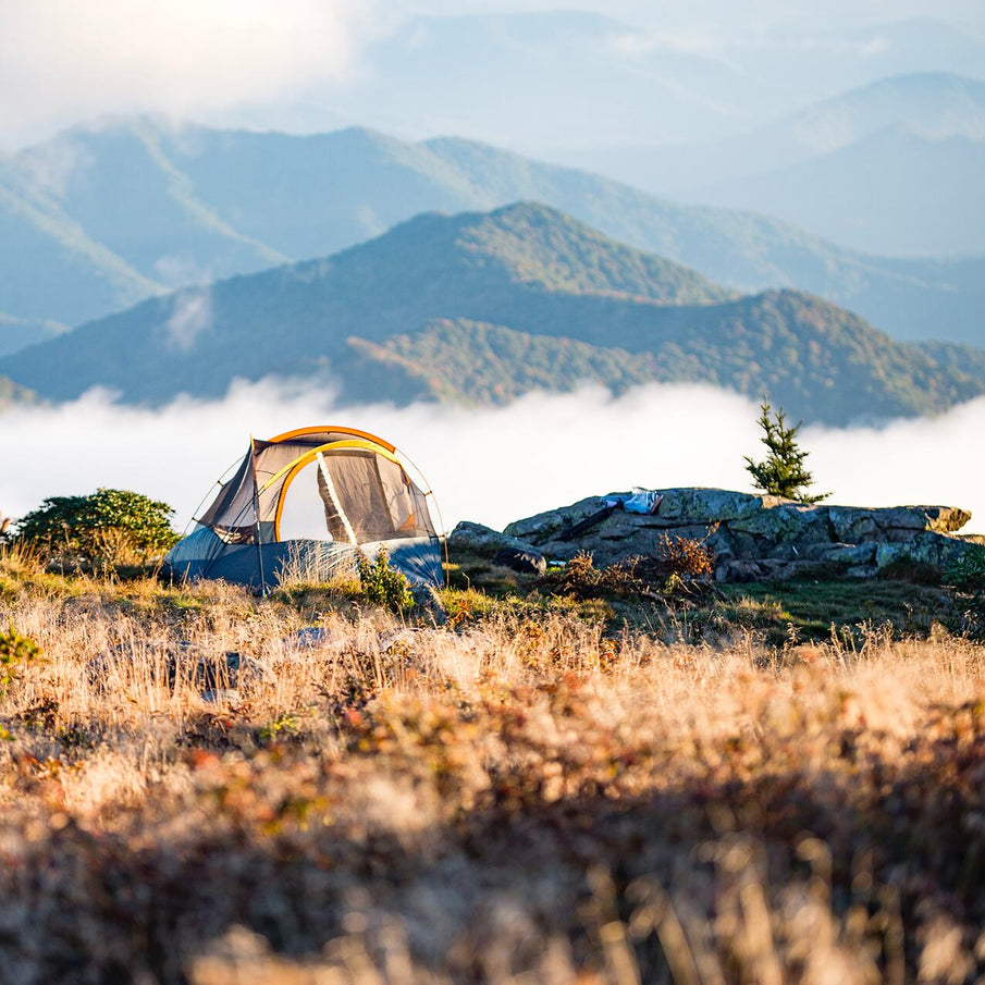 Tente de camping sur plateau de montagne, avec vue panoramique sur montagnes brumeuses 