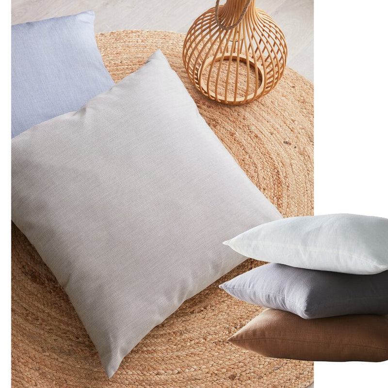 Coussins en lin aux couleurs neutres posés au sol sur un tapis en jute