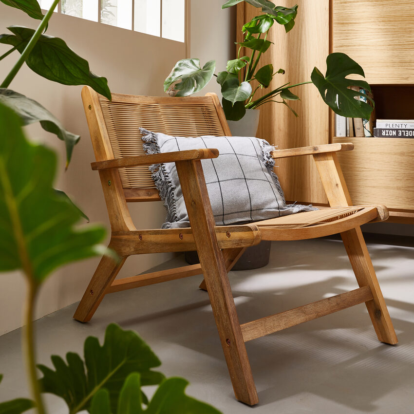 Fauteuil lounge en bois et matières naturelles, entouré de plantes vertes