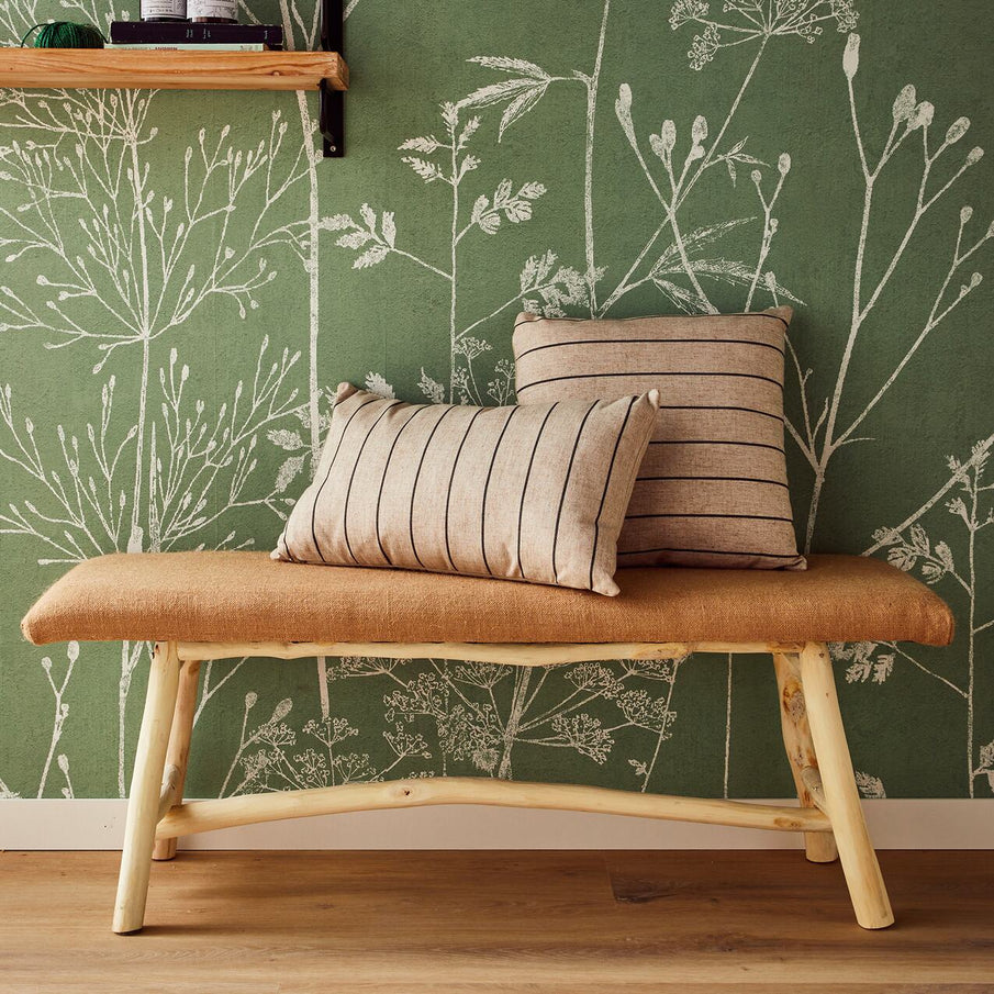 Banc en bois et jute avec coussins rayés devant un papier peint vert à motif floral blanc