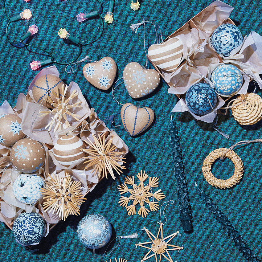 Deux boites de boules de Noël et étoiles en pailles sur un fond bleu paon