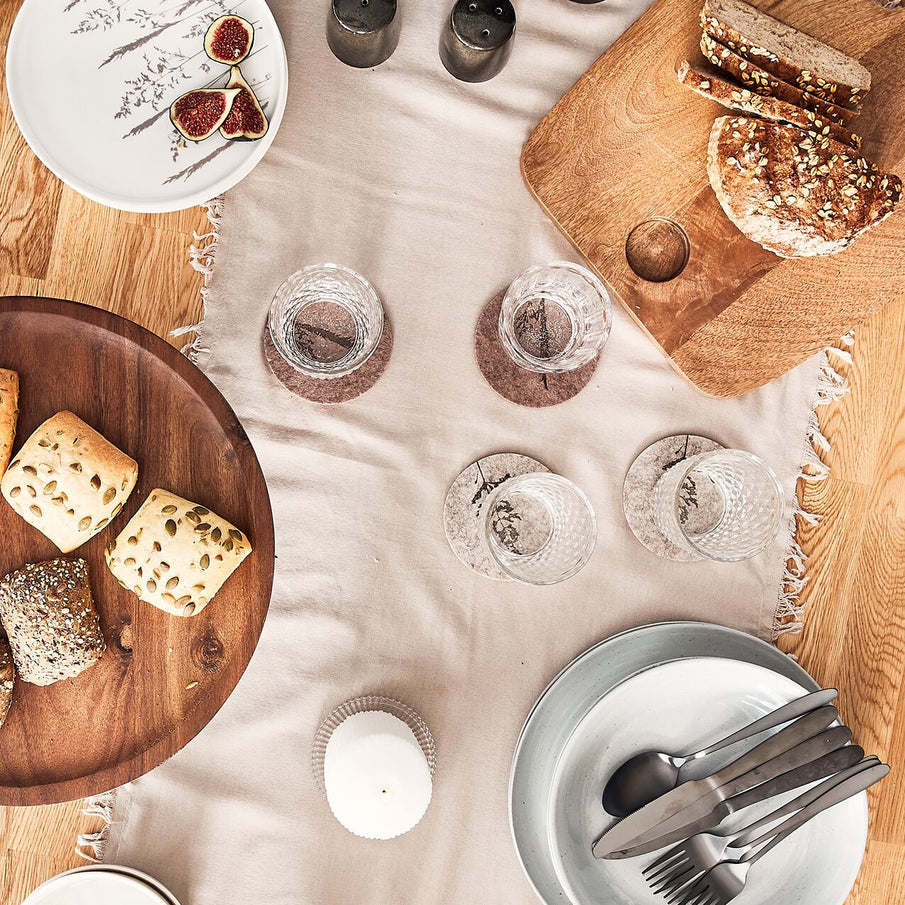 Table vue du dessus, en cours de dressage avec vaisselle et pains sur planches