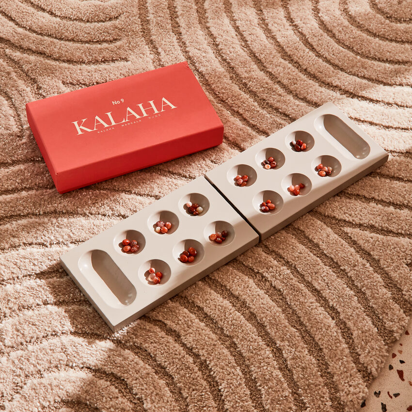 Jeu de Kalaha posé sur un tapis au motif arrondi