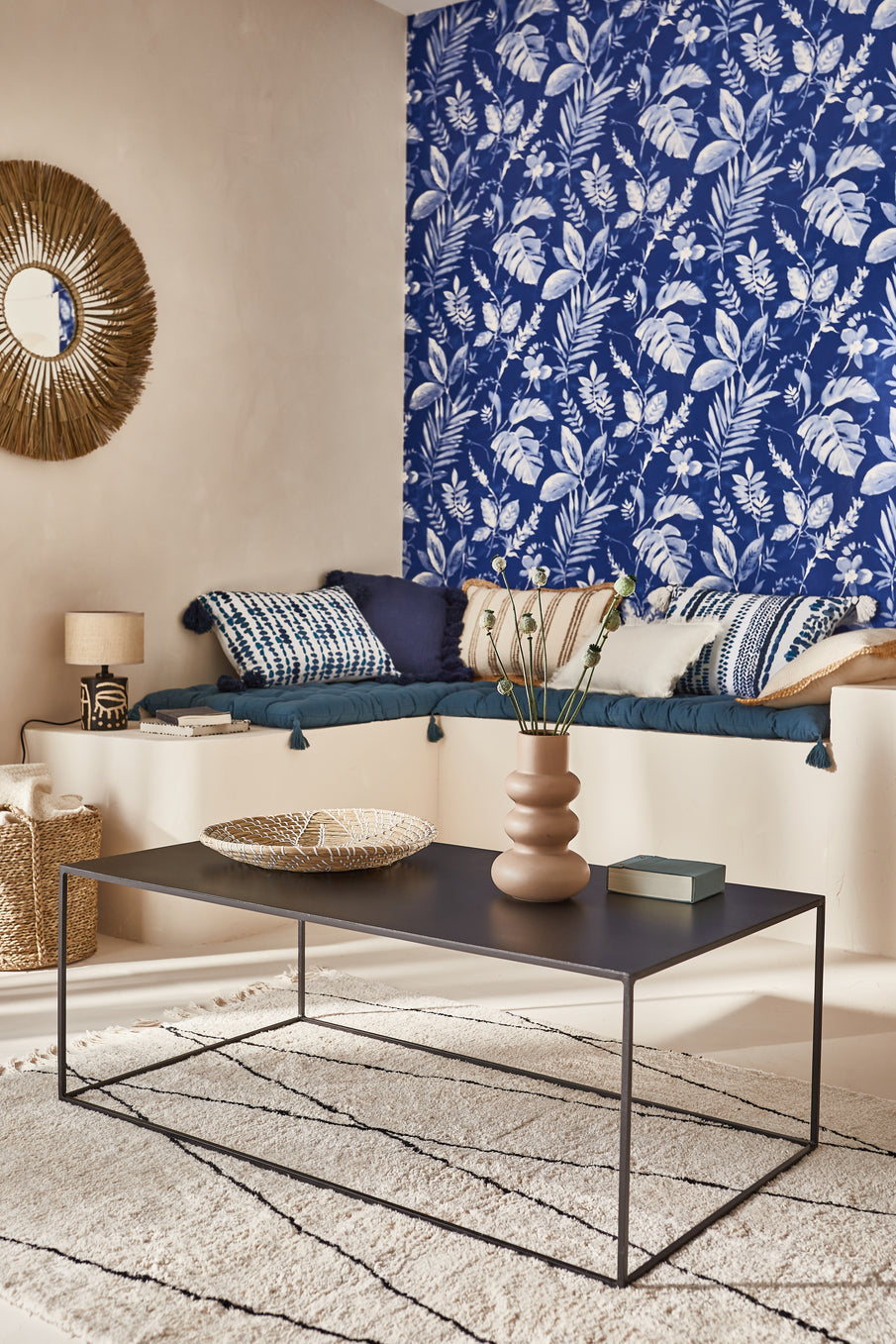 Papier peint bleu à motif végétal, banquette, table basse noir
