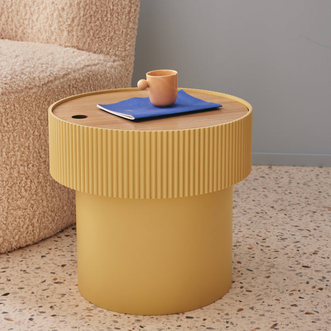 Petite tasse posée sur une table basse d'appoint ronde et jaune clair en bois