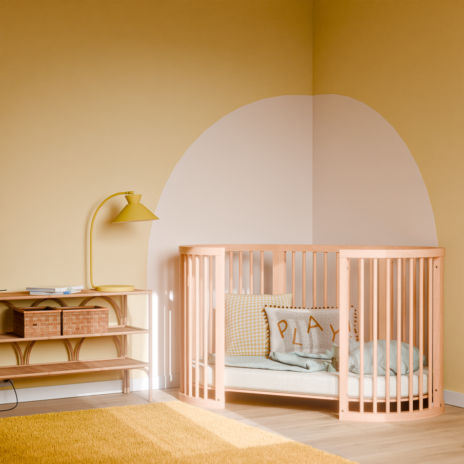 Chambre bébé en camaieu de jaune avec lit à barreaux rose, tapis et lampe jaune