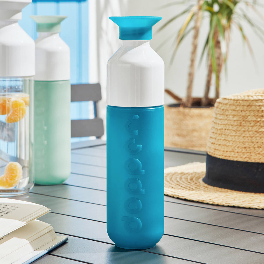 Gourde bleu de la marque Dopper posée sur une table en extérieur