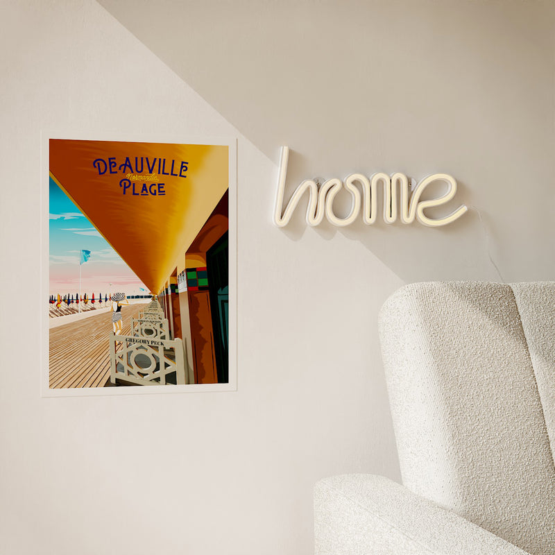 Néon mural Home allumé accroché au mur blanc avec une affiche Deauville Plage